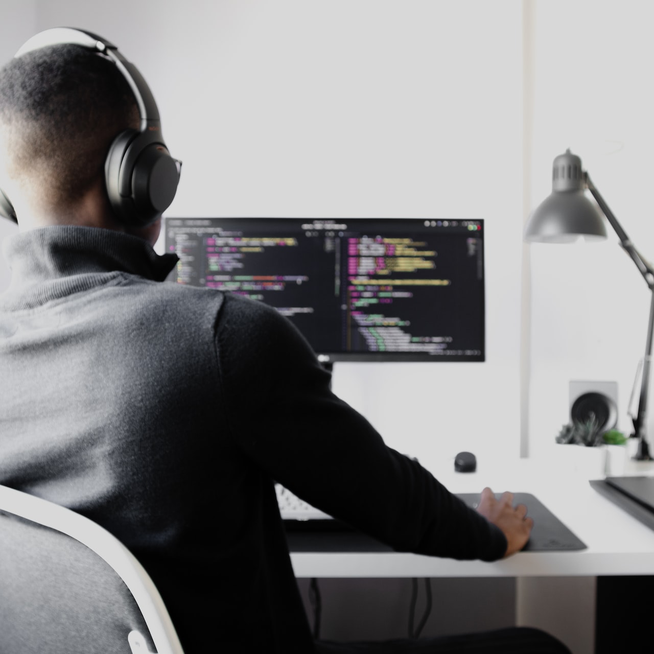 man in black long sleeve shirt wearing black headphones sitting on chair